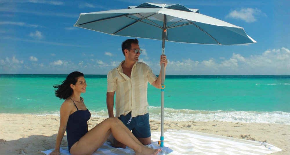 Reflective UPF 55+ silver-lined beach umbrella anchored in sand, casting steady shade.