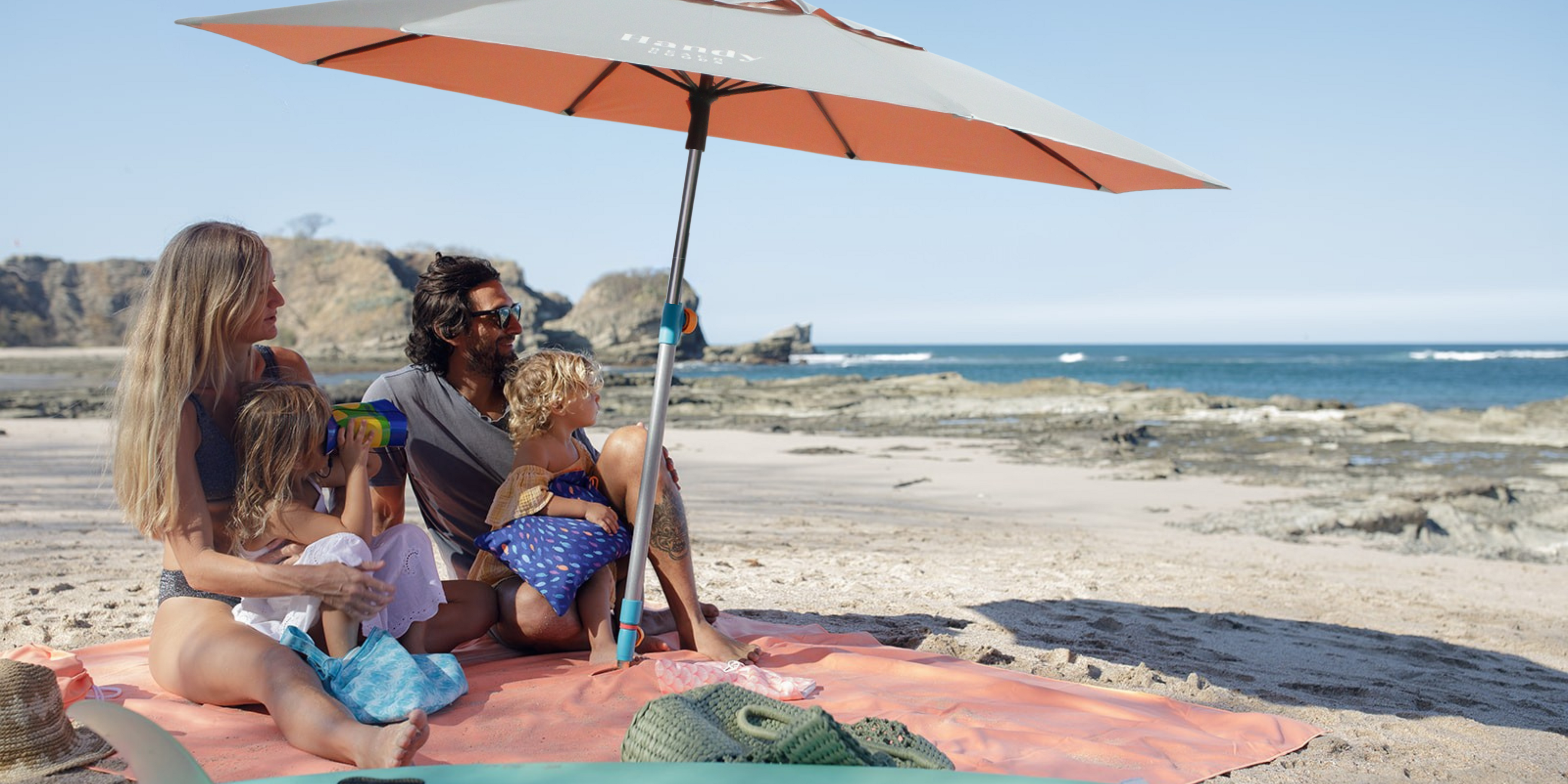 A family relaxes under a beach umbrella. | Handy Beach Goods