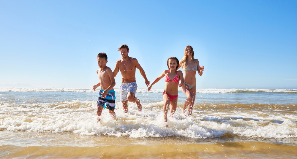 Happy family running on the beach enjoying a sunny Spring Break vacation