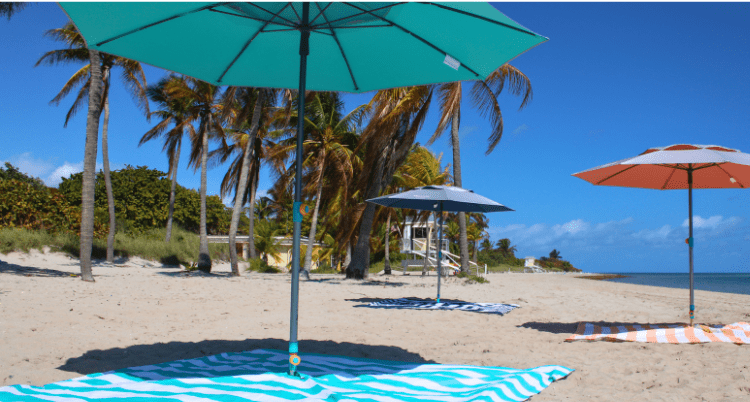 The Handy Beach Umbrella standing firmly in coastal winds, serving as a quiet, heavy-duty, and legally compliant alternative to wind-powered beach shades.