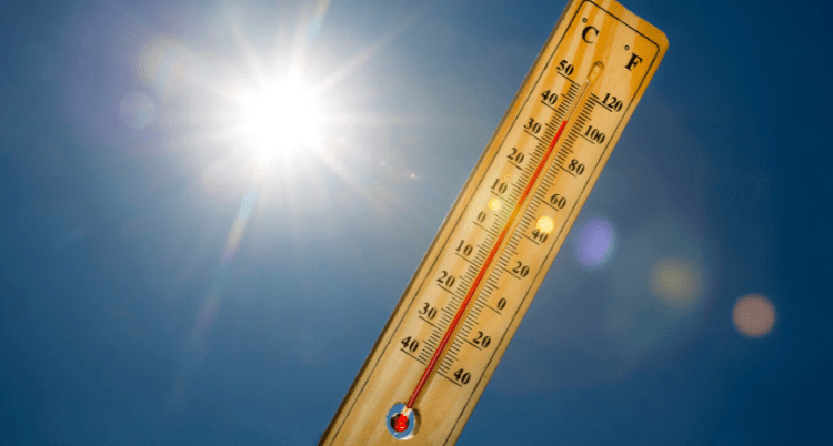 A thermometer displaying soaring temperatures during a summer heat wave, highlighting the extreme beach heat and the need for a thick, UPF 55+ beach umbrella to stay cool.