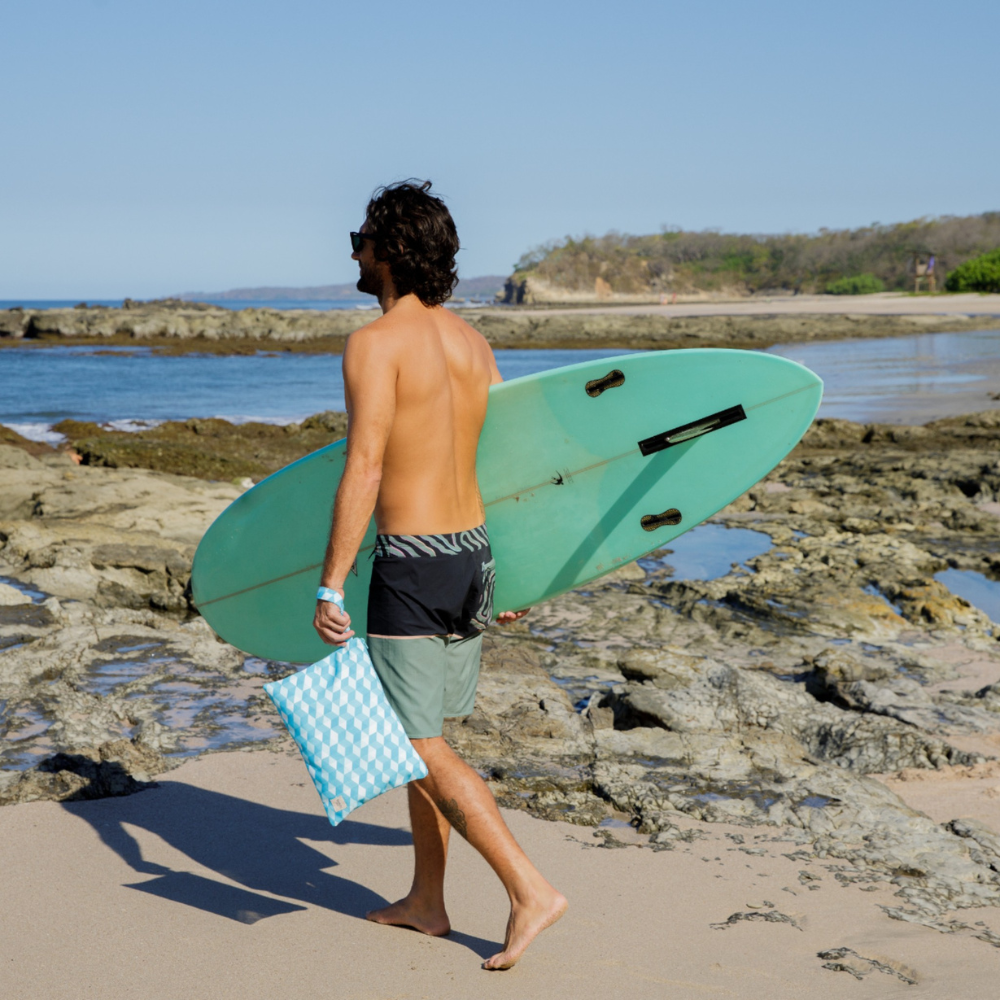 Person holding the Sea Mosaique beach wristlet bag by Handy Beach Goods, showing the ultimate beach organizer in use.