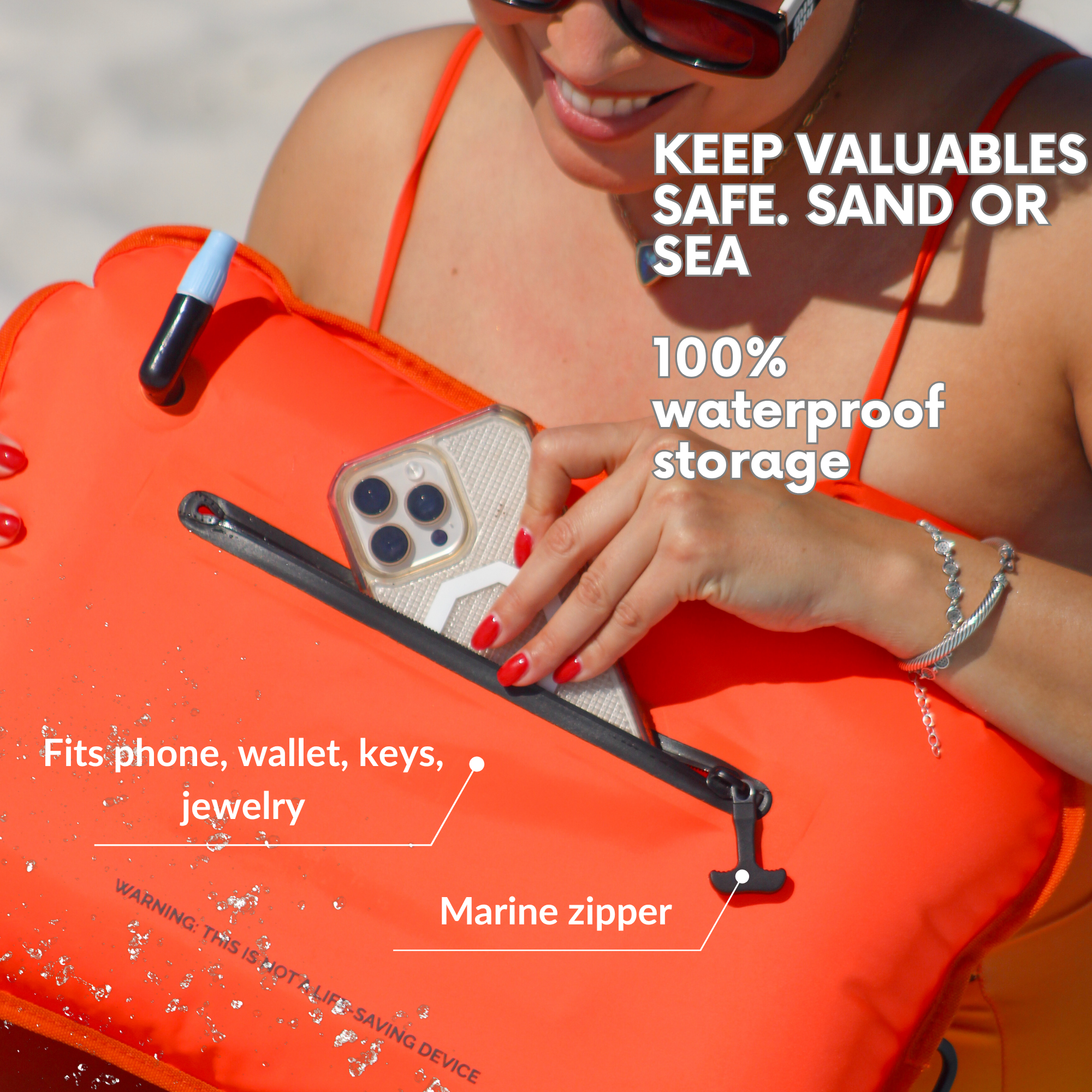 Person holding an orange waterproof pocket with phone inside, beach setting.