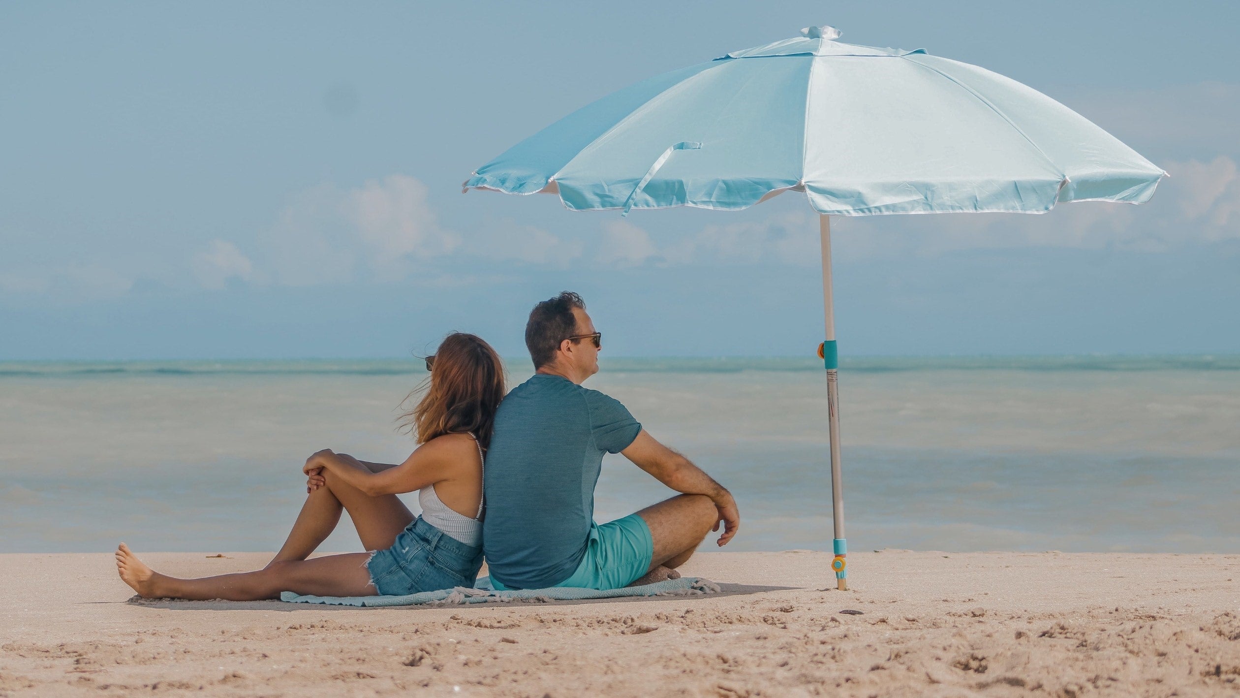 A couple enjoying beach life while using a Handy Beach Anchor and umbrella