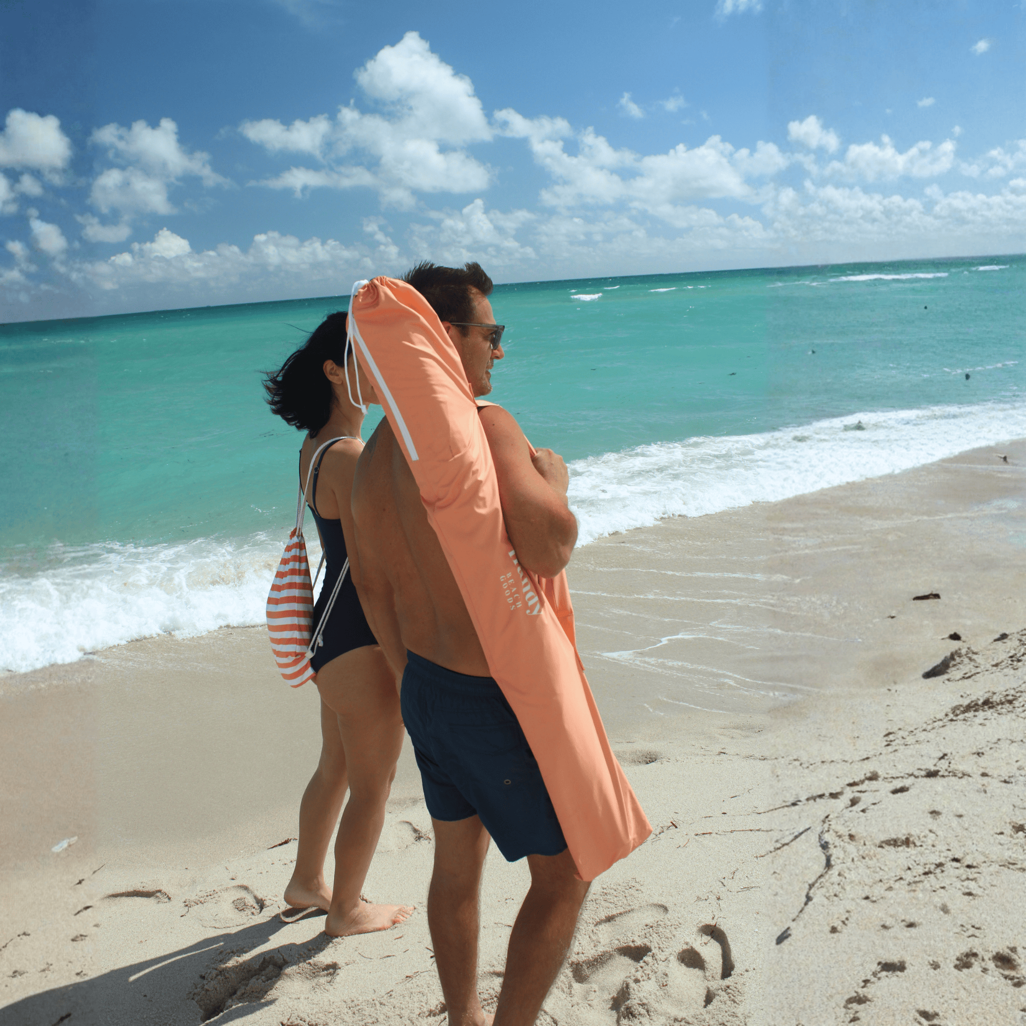 Easy to pack beach umbrella carried by a couple. peach umbrella system 