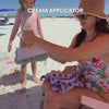 Mother at the beach using the white non-absorbent side of the Handy glove to quickly and smoothly apply sunscreen to her child's legs.
