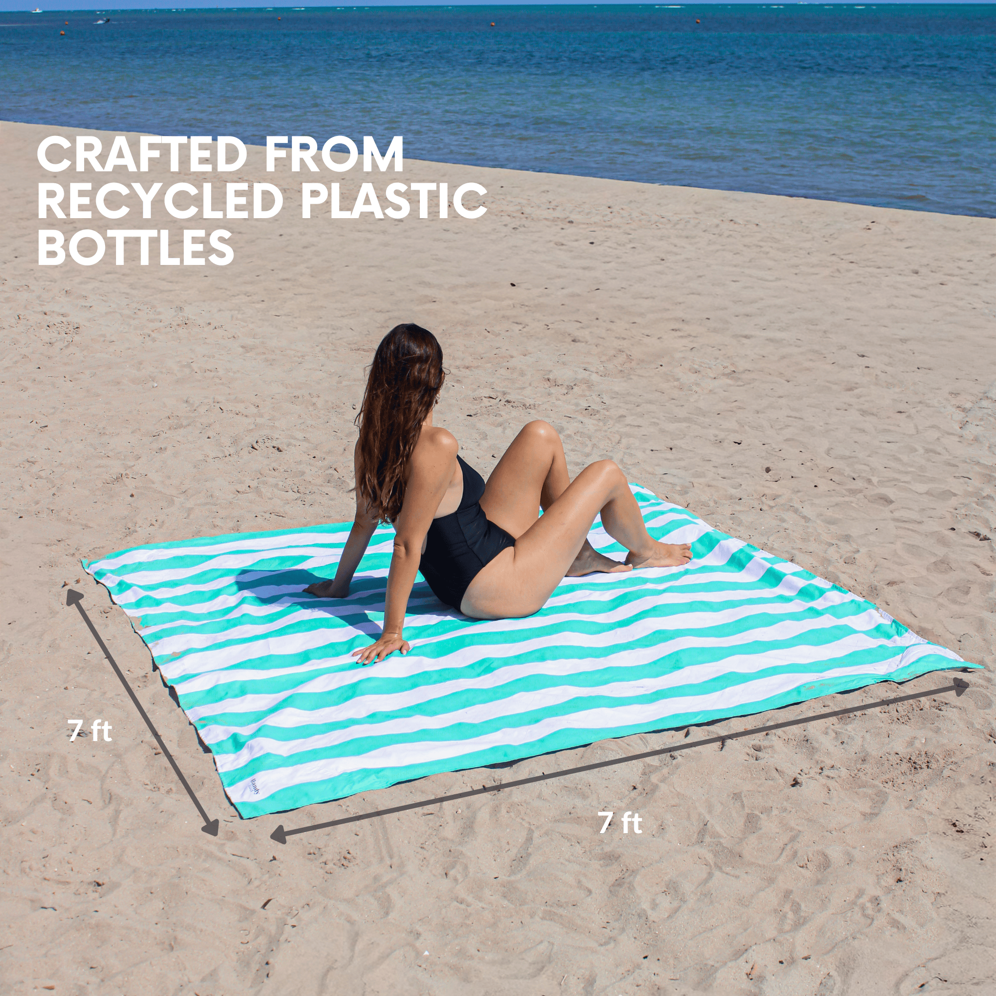 Woman sitting on an oversized 7x7 ft beach blanket in teal stripes crafted from recycled materials, providing plenty of space.